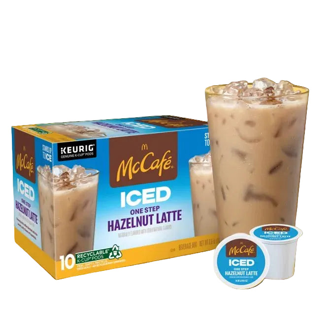 McDonald's McCafé Iced One Step Hazelnut Latte coffee pods shown with a branded retail box, two single-serve pods, and a tall glass of iced latte on a solid yellow background.